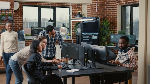A diverse team of software developers working collaboratively in a modern, open-plan office. Laptops and multiple screens display lines of code, highlighting the focus on technology and innovation.