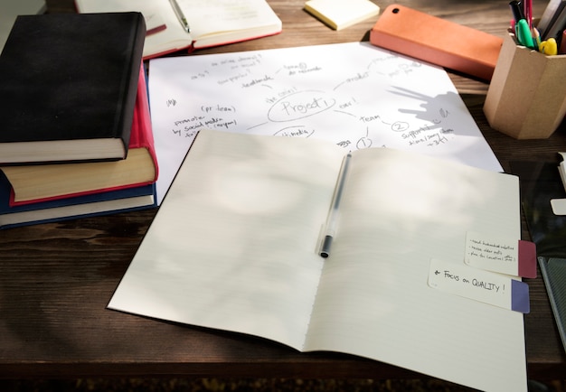 A close-up of an open examination booklet with handwritten notes and formulas. A pen is placed on top of the booklet, and a pair of glasses rests beside it. The image conveys the intensity and effort involved in taking the ENEM.