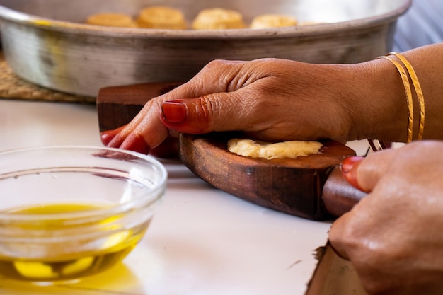 Close-up of a Baiana selling Acarajé in Salvador, Bahia, showing the traditional clothing and the process of preparing the Acarajé. The background includes colorful colonial architecture.