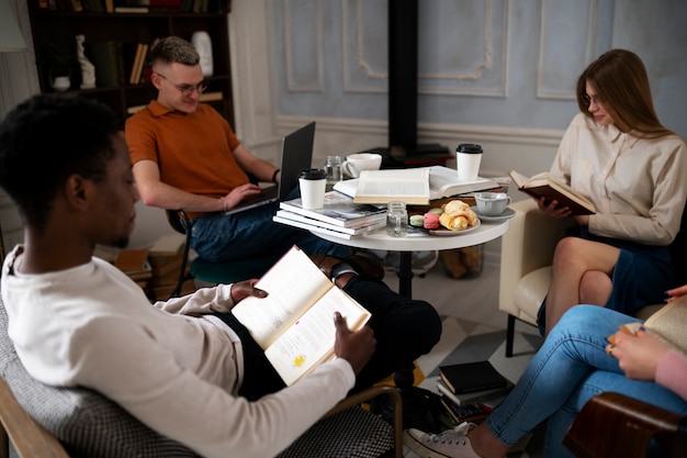 A photograph of a diverse group seated thoughtfully in a book club meeting inside a warmly lit library. Books are scattered on the table in front of them, with each member holding a copy. Emphasis on varied ethnicities and ages to showcase inclusivity.