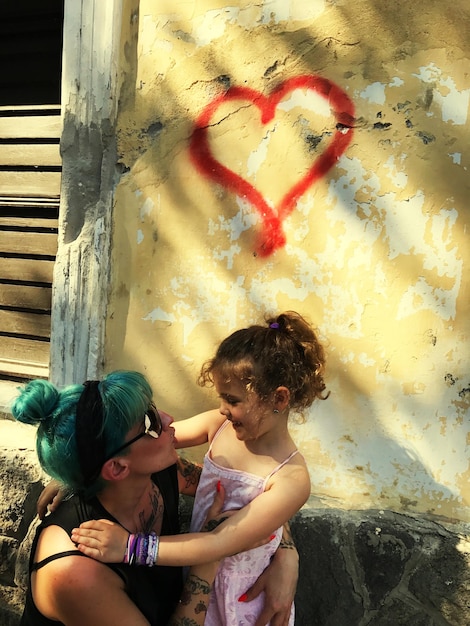 A group of children in a Brazilian favela participating in a painting workshop led by a local artist. The children are smiling and engaged, creating colorful artwork. The background shows the simple houses and narrow streets of the favela.