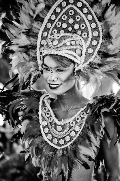 A black-and-white photograph depicting a street carnival parade in Rio de Janeiro in the early 20th century, showing participants in masks and elaborate costumes, accompanied by musical bands.