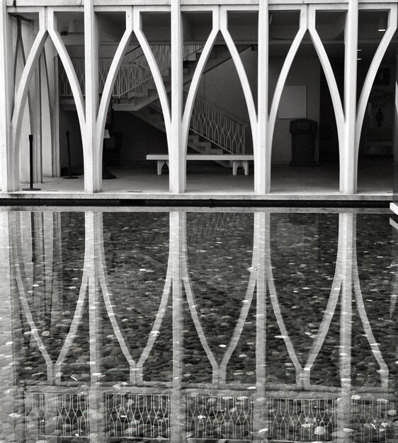 A striking angled shot of the Palácio da Alvorada in Brasília, Brazil, designed by Oscar Niemeyer, showcasing its modern lines, white columns, and the reflection in the surrounding water.