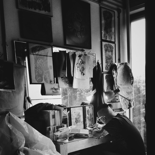 A black and white photograph of Anita Malfatti in her studio, surrounded by her paintings, capturing her intense focus and artistic dedication. Her bold, expressive style is evident in the artworks surrounding her.
