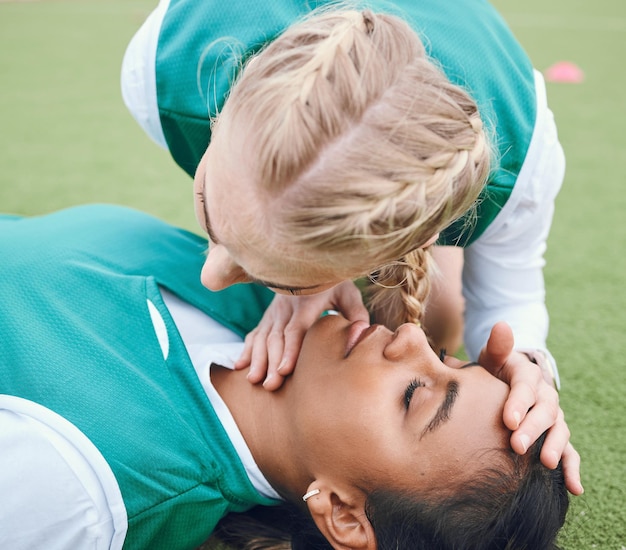A close-up of a Brazilian soccer player receiving treatment from a physiotherapist on the sidelines during a match, showing concern on his face.