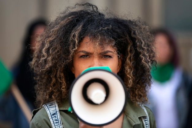 A close-up shot of a community leader in Brazil, using a megaphone to address residents in a bustling street. The leader appears strong and determined, with the residents listening attentively, showing the impact of direct communication in mobilizing people.