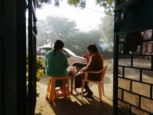 A heartwarming scene showing a Brazilian community leader sitting on the porch of a resident's house, engaging in a friendly conversation. Both are smiling, creating a sense of trust and camaraderie, illustrating the importance of personal connection in community leadership.