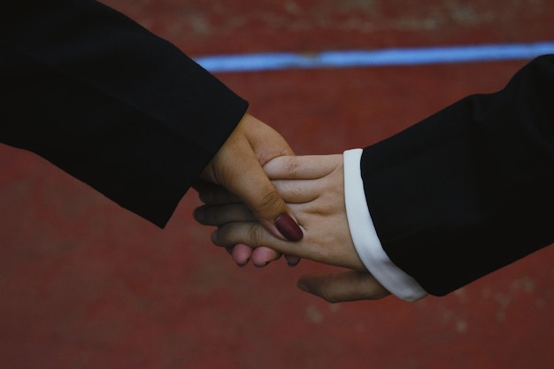 Close-up of the hands of two business people (one is Luiza Trajano) shaking hands symbolically over a digital tablet displaying plans for sustainable business practices, exemplifying ethical business development.