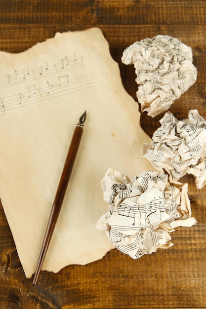 A close-up overhead shot of a vintage sheet music of the Brazilian National Anthem, showcasing intricate musical notes and faded ink, with a quill pen resting on top.
